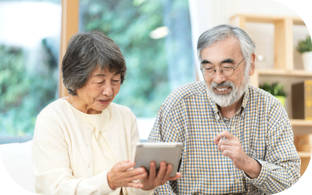 リビングでタブレットを使って暮らしぶりチェック項目を確認するじいじとばあばの様子