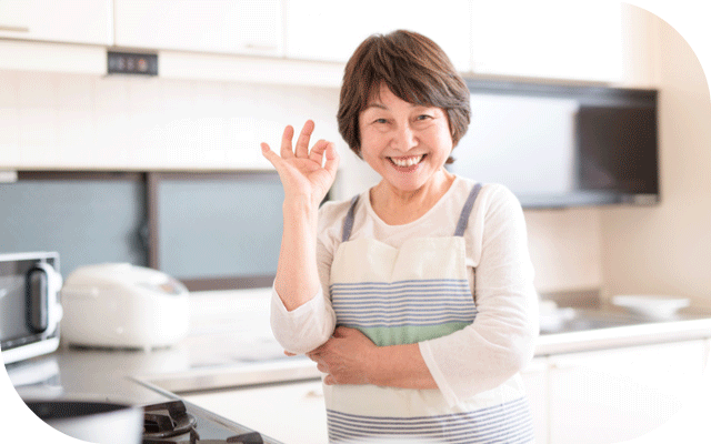 整ったキッチンでオーケーサインをするばあばの写真