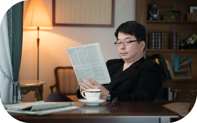 書斎で紅茶を飲みながら新聞を読むじいじの写真