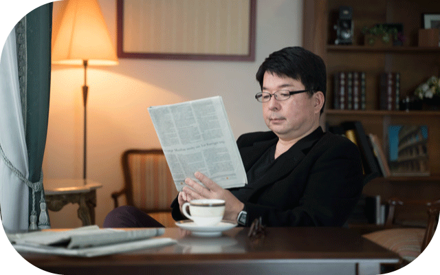 書斎で紅茶を飲みながら新聞を読むじいじの写真