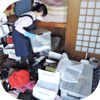 整えサポーターがプラスティックの衣装ケースの衣類を分別し、コンパクトな収納バッグへ入れ替えている様子