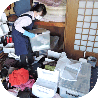 整えサポーターがプラスティックの衣装ケースの衣類を分別し、コンパクトな収納バッグへ入れ替えている様子